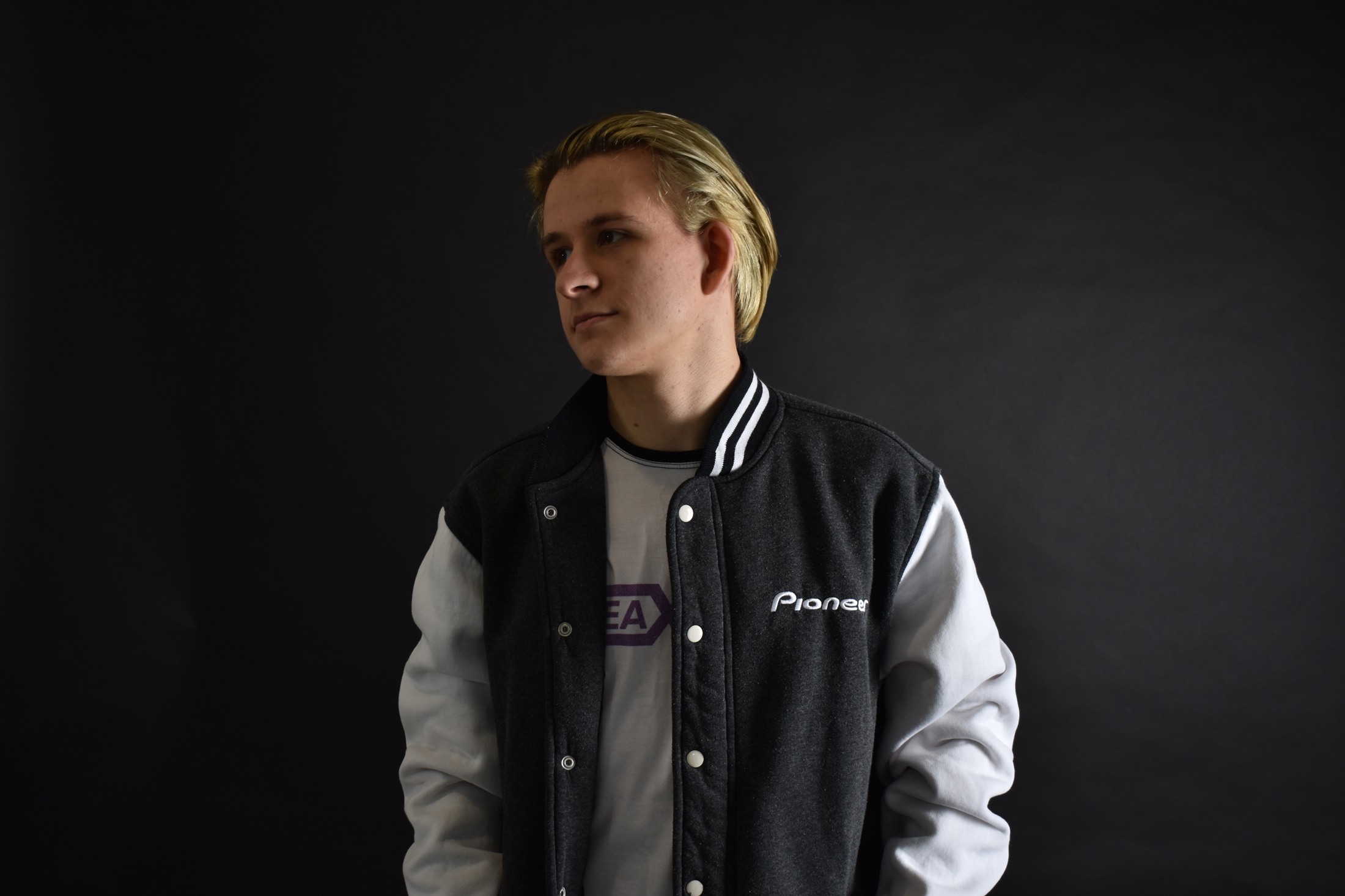Freaxment wearing a black and white jacket against a dark studio background